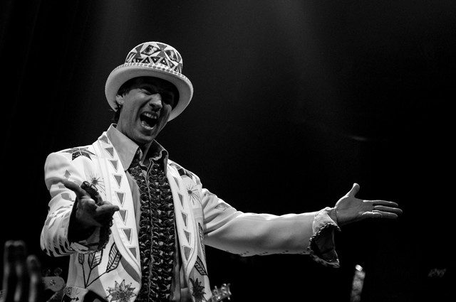 Performer in ornate suit and hat gesturing.