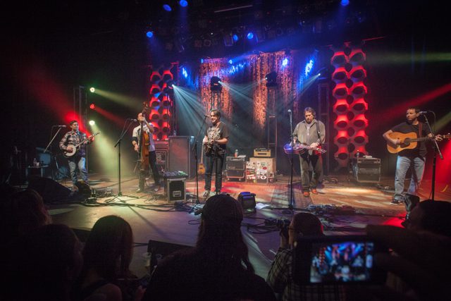 Band performing on stage with colorful lights.