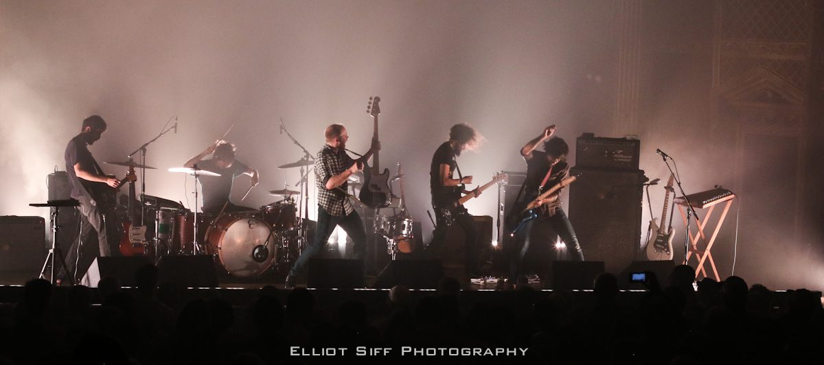 Rock band performing energetically on stage.