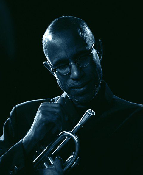 Musician holding trumpet in dim lighting.