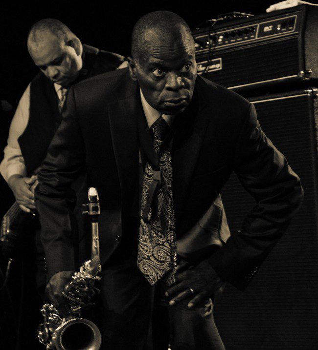 Musicians performing with a saxophone on stage.
