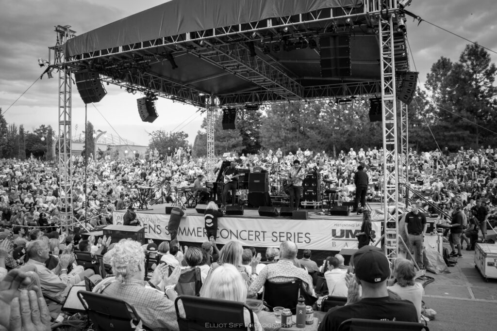 Outdoor concert with large seated audience.