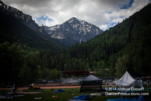 Mountain campsite with tents and cloudy sky.