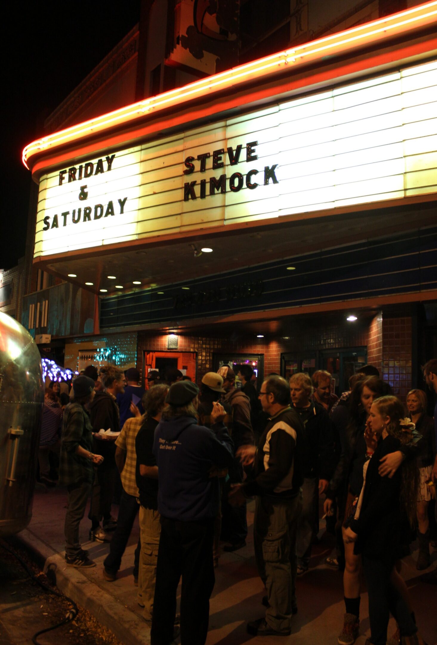 Crowd outside venue with event marquee.