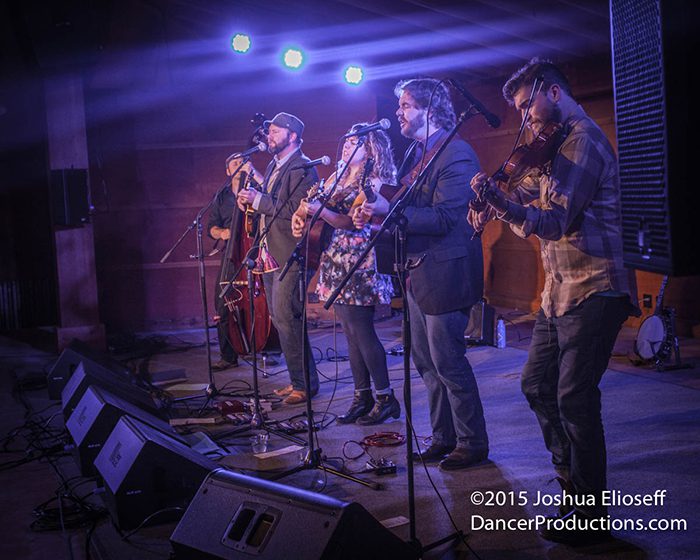 Band performing live on stage with instruments.