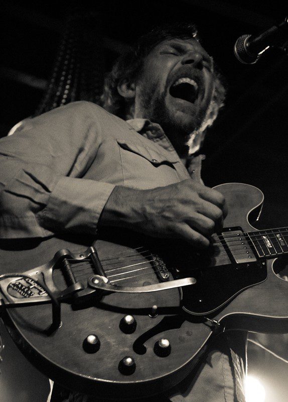 Musician passionately playing electric guitar on stage.