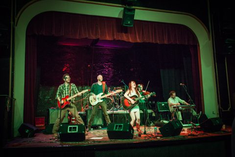 Band performing on stage with instruments.
