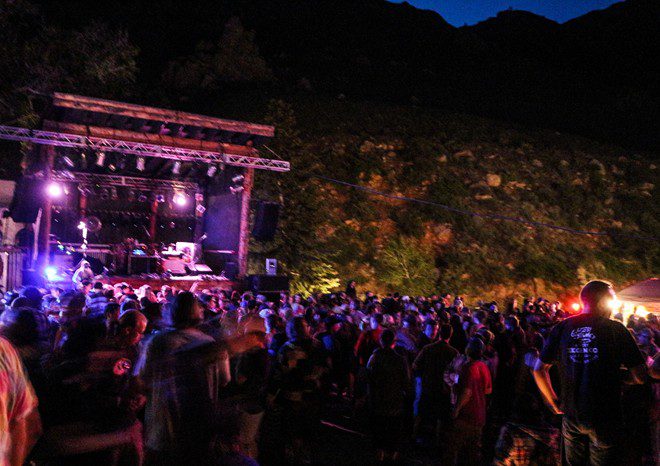 Outdoor concert crowd at night with stage.