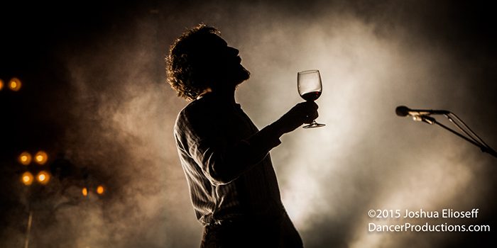 Silhouette of person holding a wine glass.