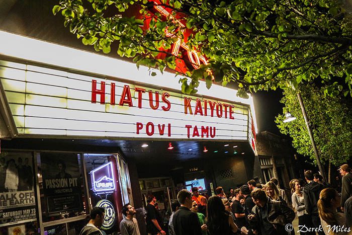 Crowd outside theater with marquee at night.