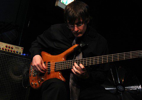 Musician playing bass guitar on stage.