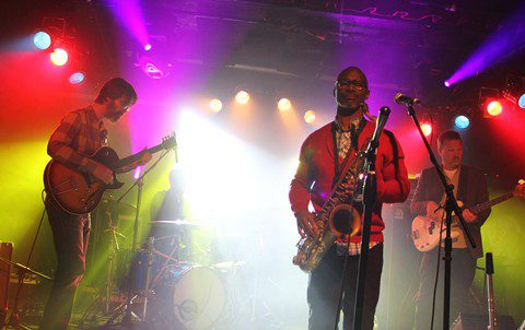 Band performing on stage with colorful lights.