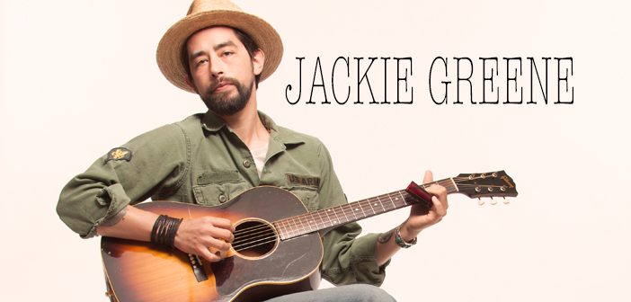 Man playing guitar with hat and harmonica.