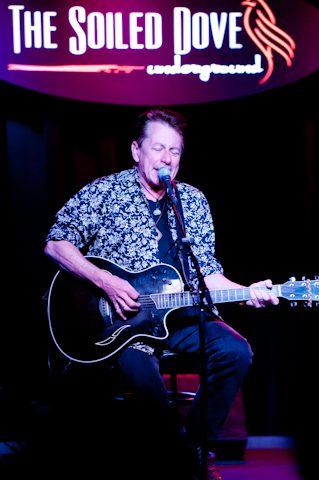 Musician performing with guitar on stage.