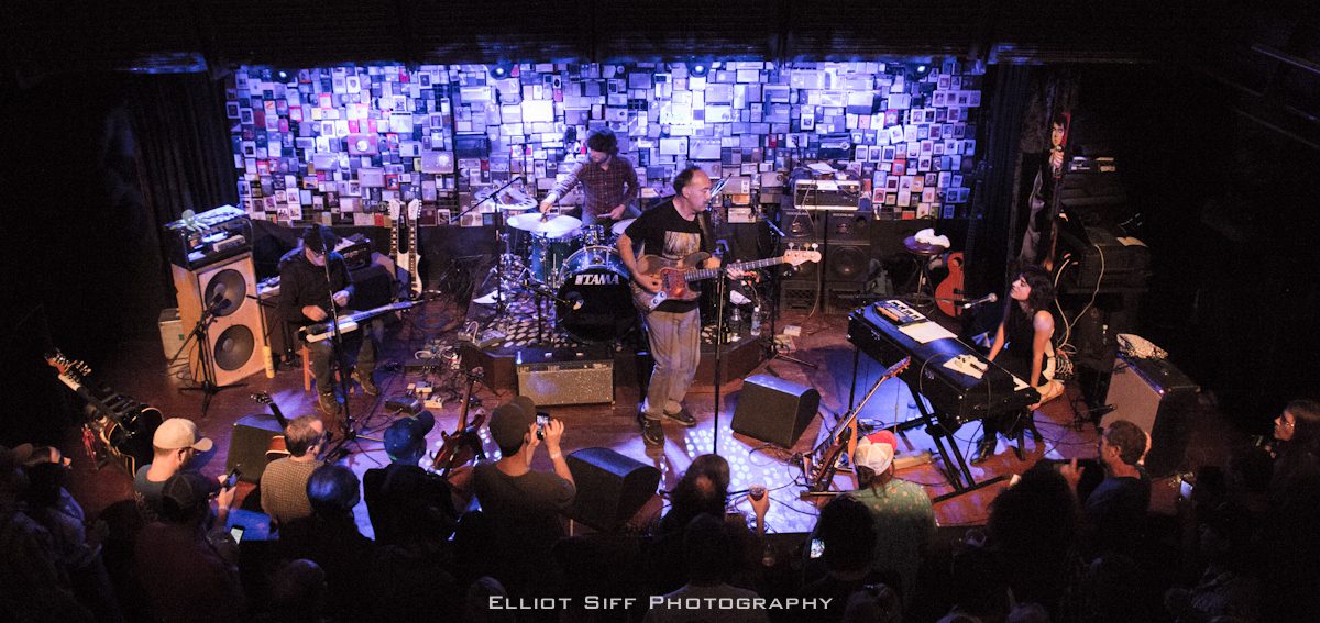 Band performing on stage with audience watching.