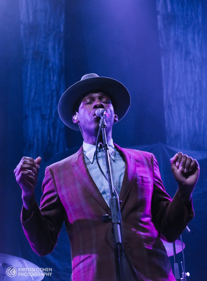 Singer in a hat performing on stage.
