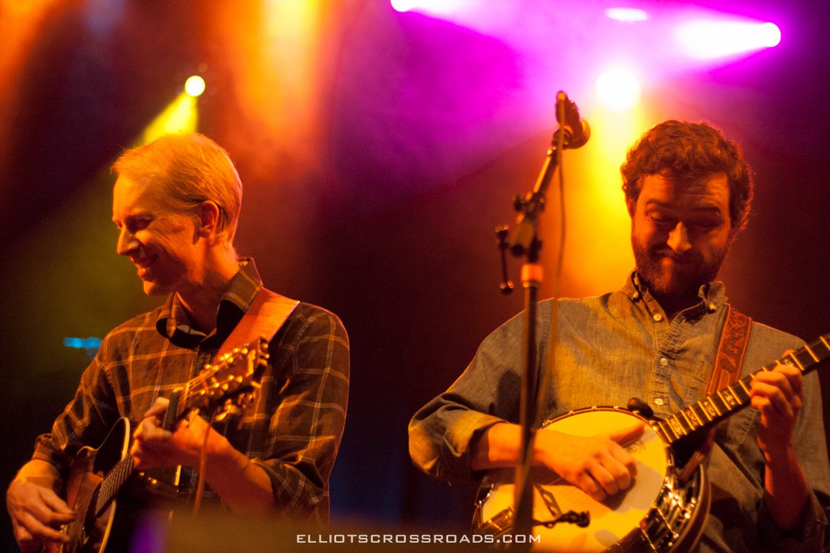 Two musicians playing guitars on stage.