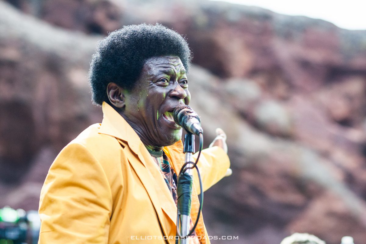 Singer performing outdoors in yellow suit.