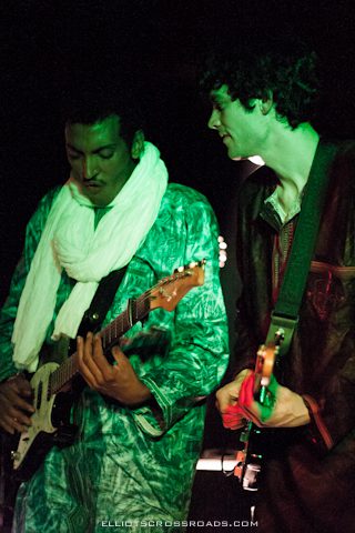Two musicians playing guitars on stage.