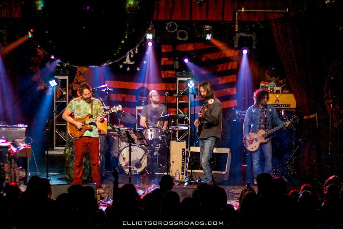 Band performing live on stage with lights.
