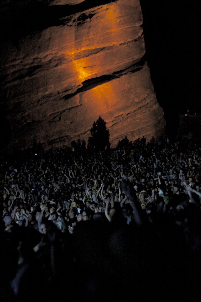 Concert crowd under illuminated rock formation.