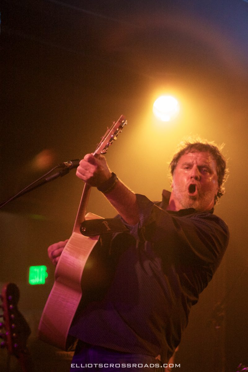 Musician performing energetically with a guitar.