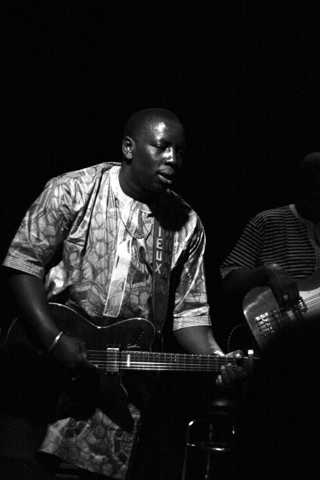 Musician playing electric guitar on stage.