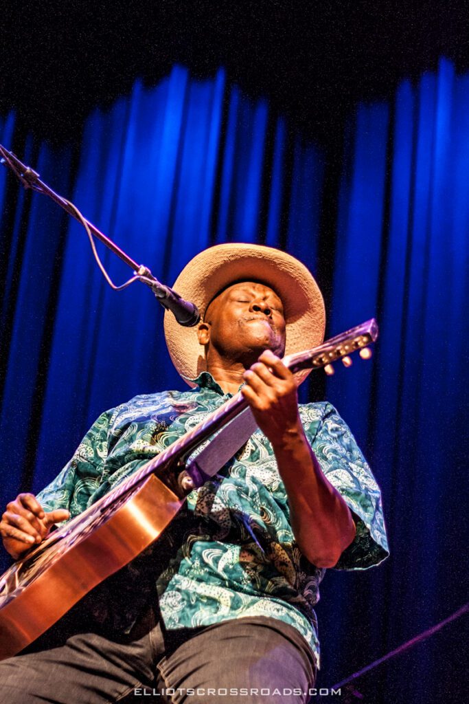 Musician performing with guitar on stage.