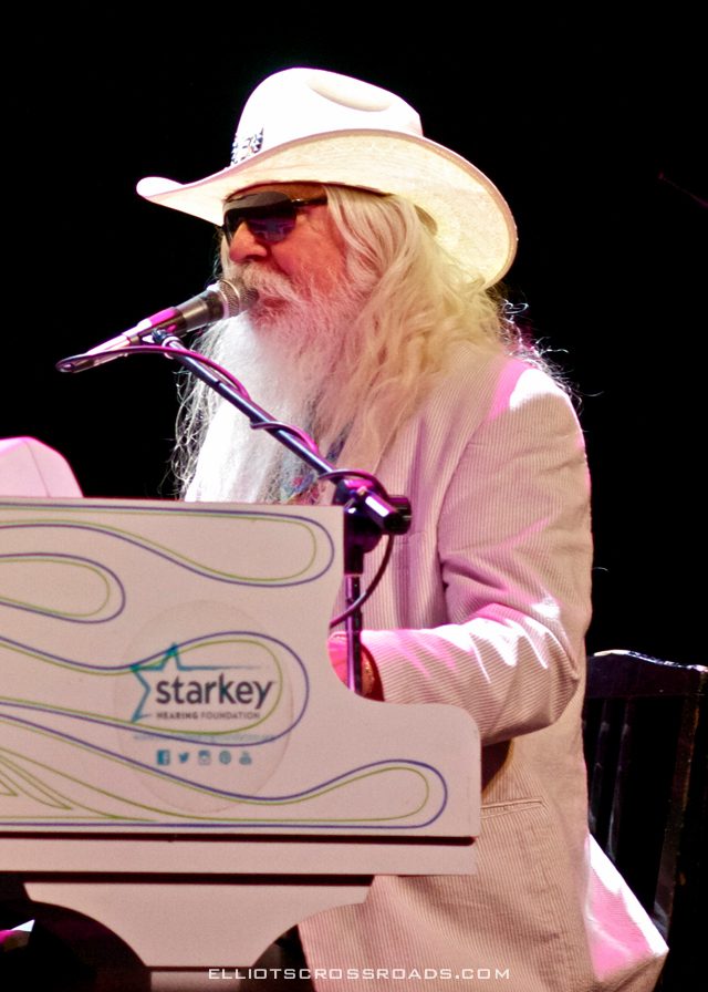 Musician in hat playing piano on stage.