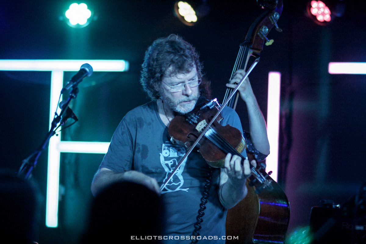 Musician playing violin on stage with lights.