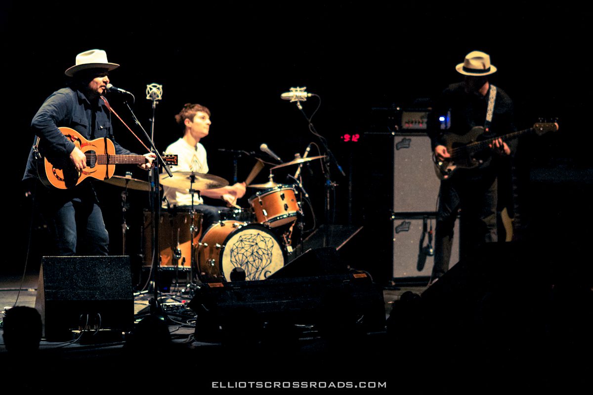 Band performing live on stage with instruments.