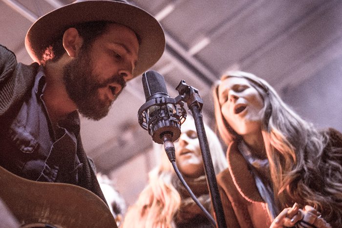 Musicians singing and playing guitar on stage.
