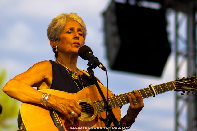 Woman performing with guitar on stage.