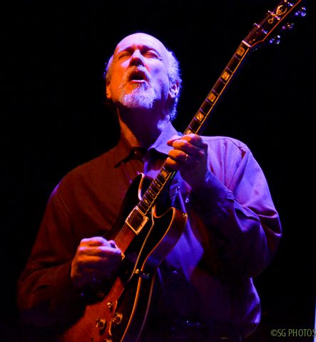 Musician passionately playing electric guitar onstage.