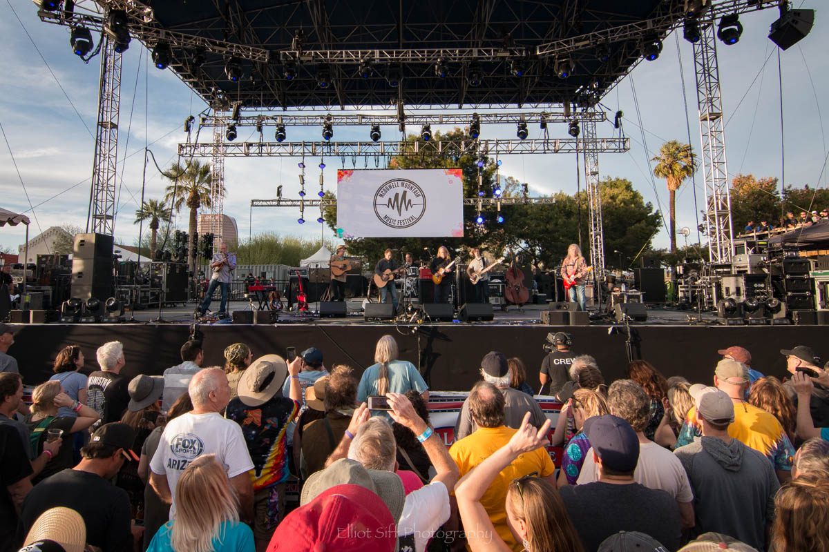 Outdoor concert with crowd and stage lights.