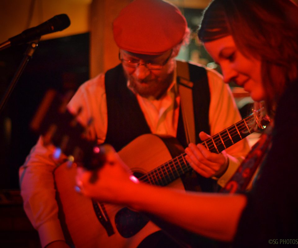 Musicians playing guitars on stage together.