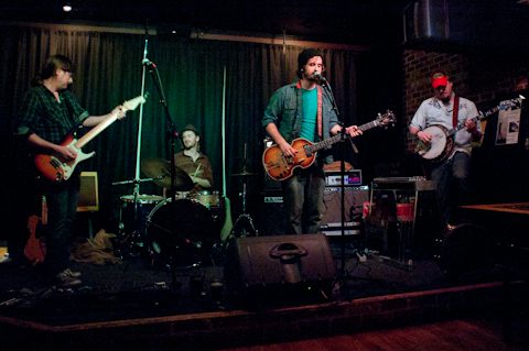 Band performing on stage with instruments.