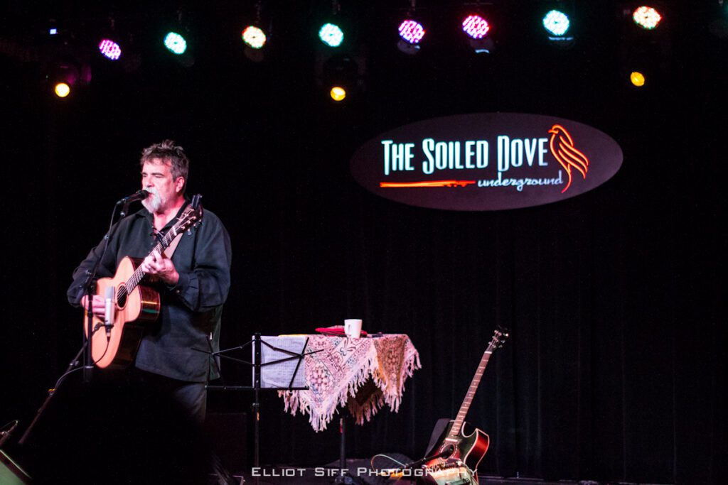 Musician performing on stage with guitar.