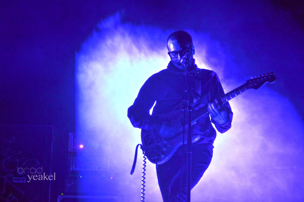 Guitarist performing on stage with blue lighting.