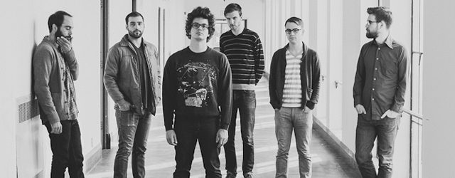 Six men standing in a hallway together.
