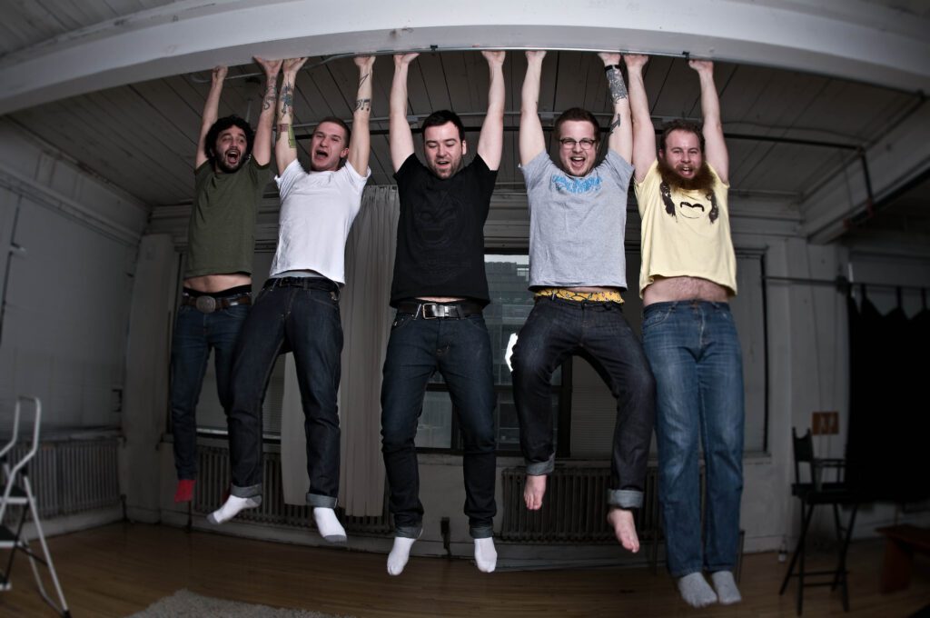 Five people hanging from a ceiling beam.