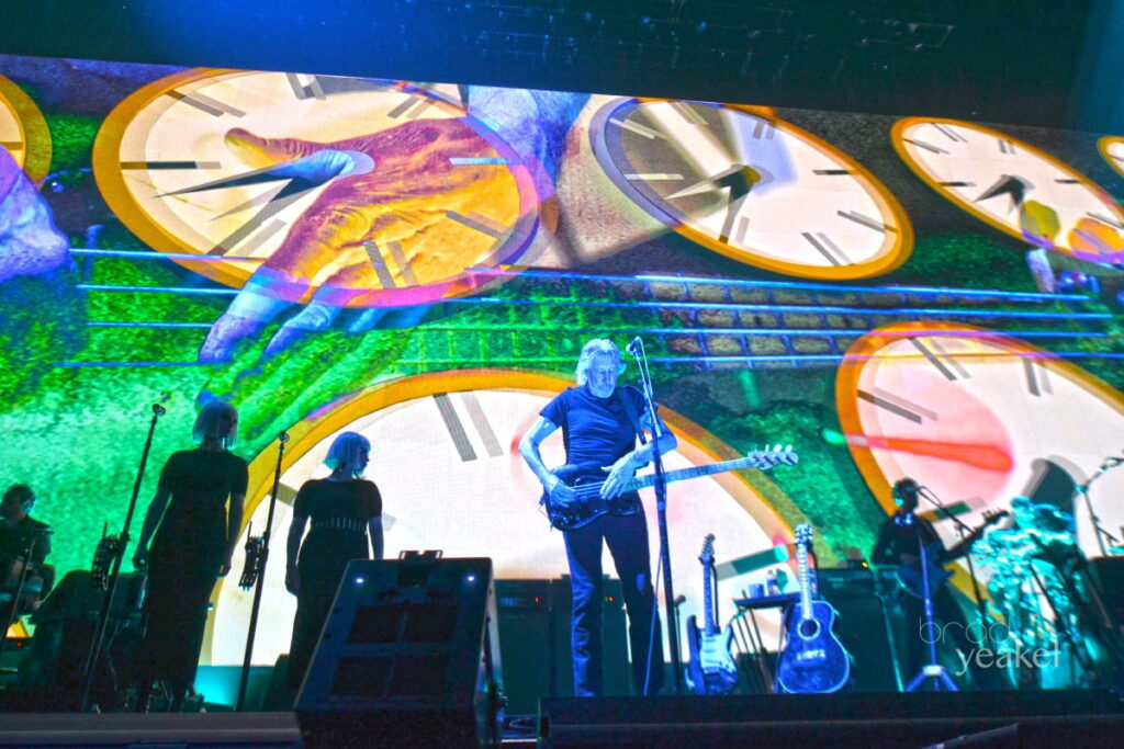 Concert stage with clocks and musicians performing.