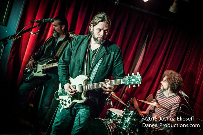 Band performing live with guitar and drums.