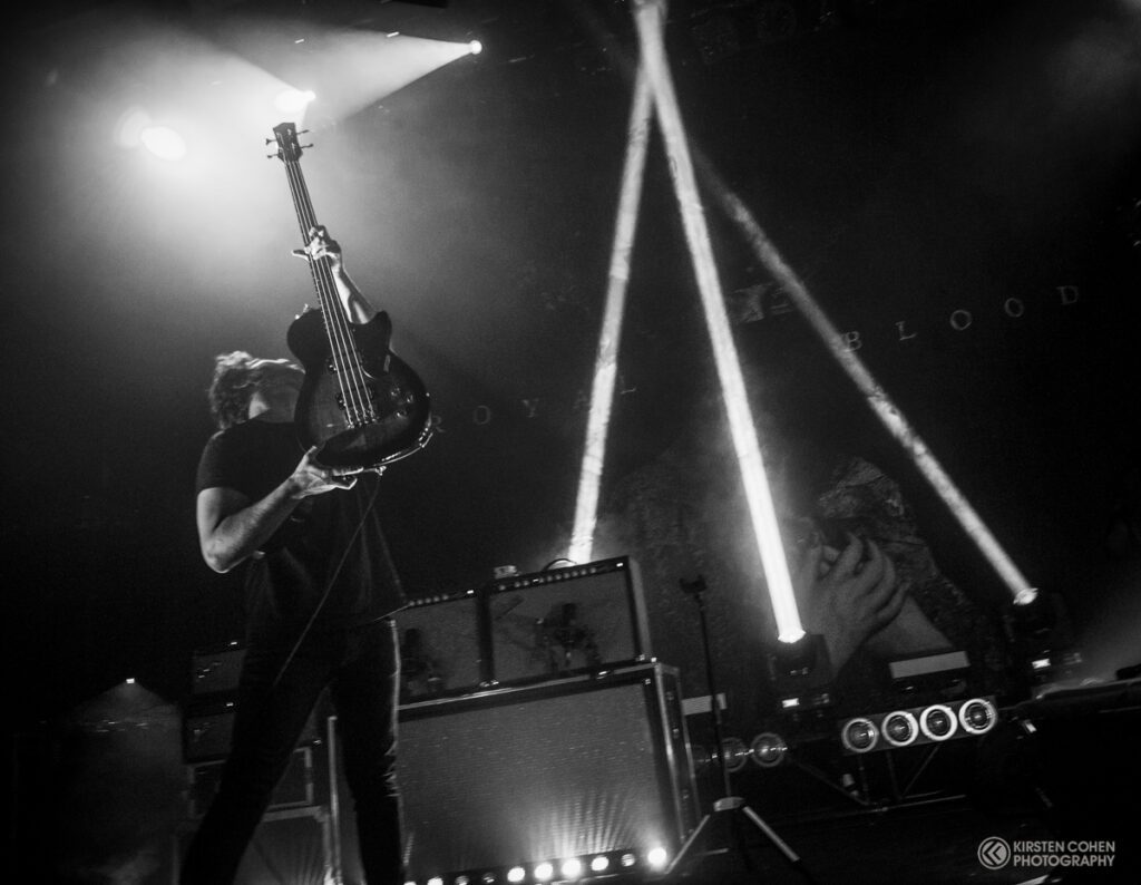 Musician performing energetically with guitar on stage.