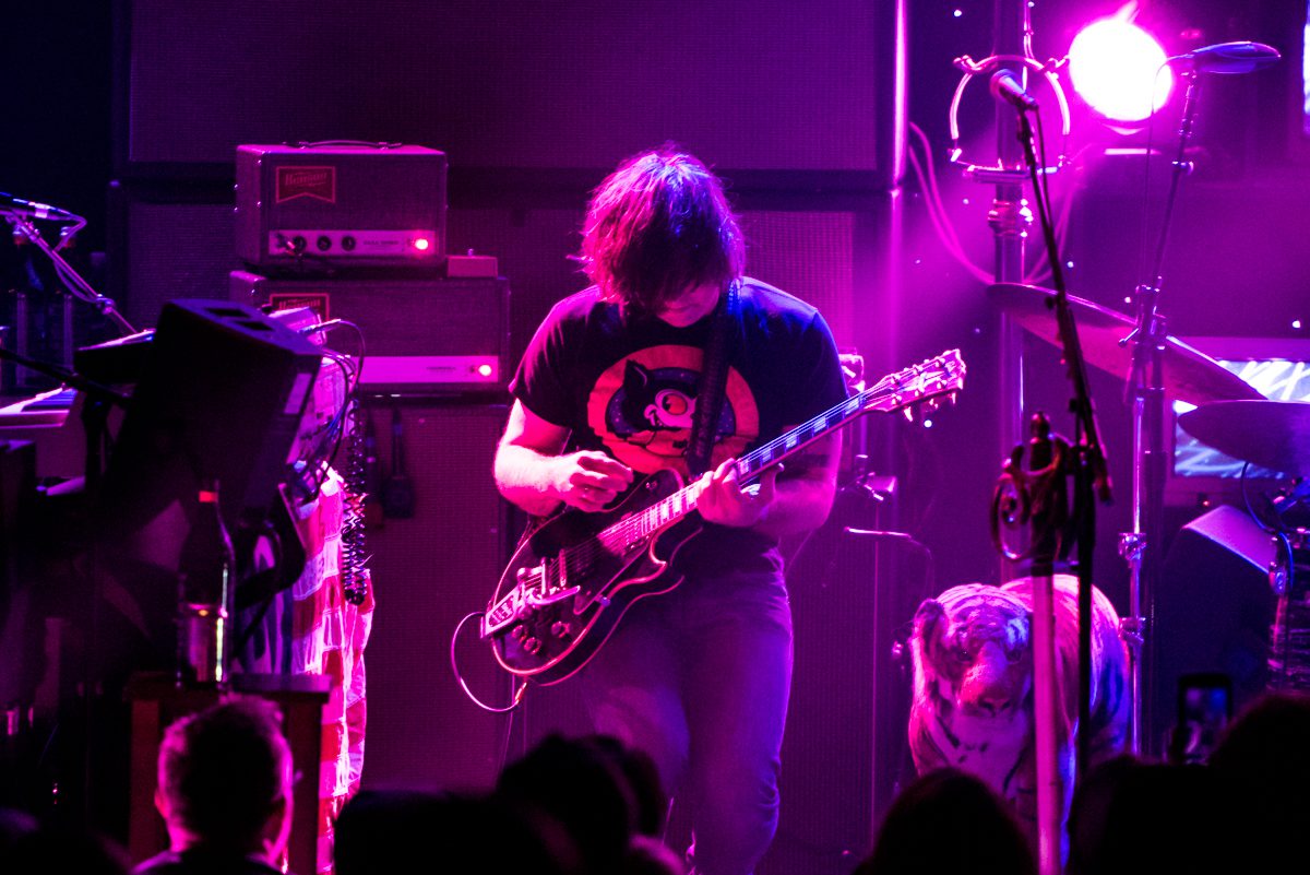 Guitarist performing on stage with vibrant lighting.