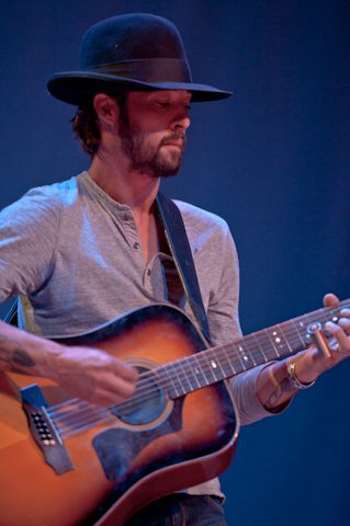Man playing acoustic guitar on stage.