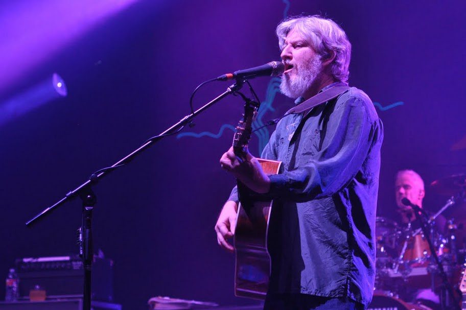 Musician performing on stage with guitar.