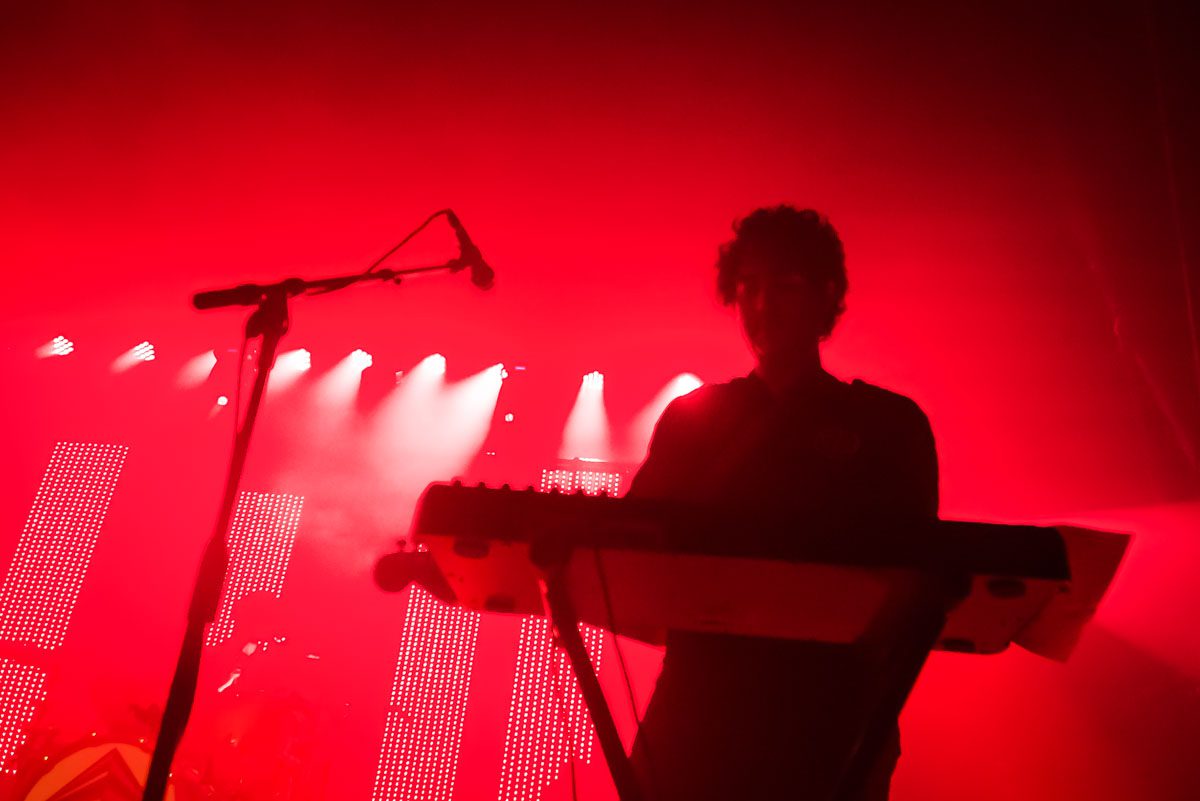 Musician performing on stage with red lighting.