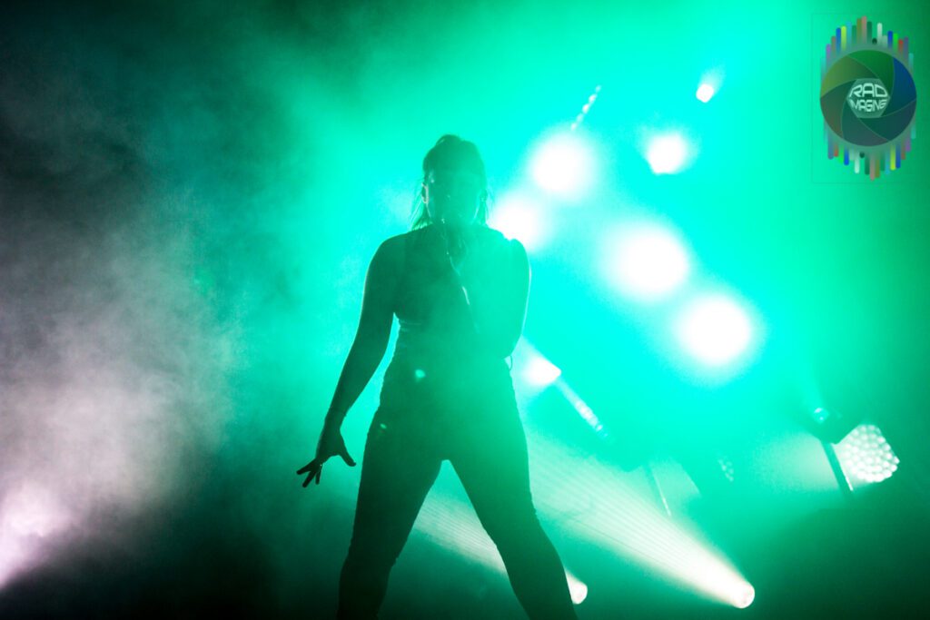 Performer silhouetted against green stage lights.