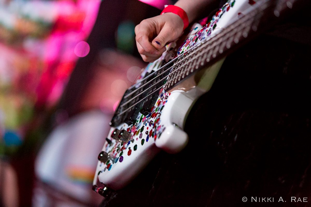 Hand playing a decorated electric guitar.
